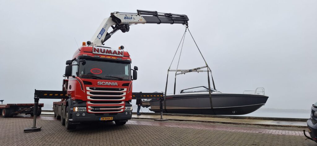 Autolaadkraan van Numan Transport met boot in kraan.